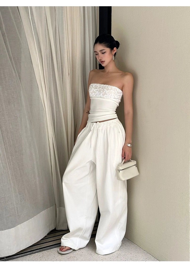 White cotton wide-leg streetwear pants styled with a lace-trim strapless top and mini white handbag