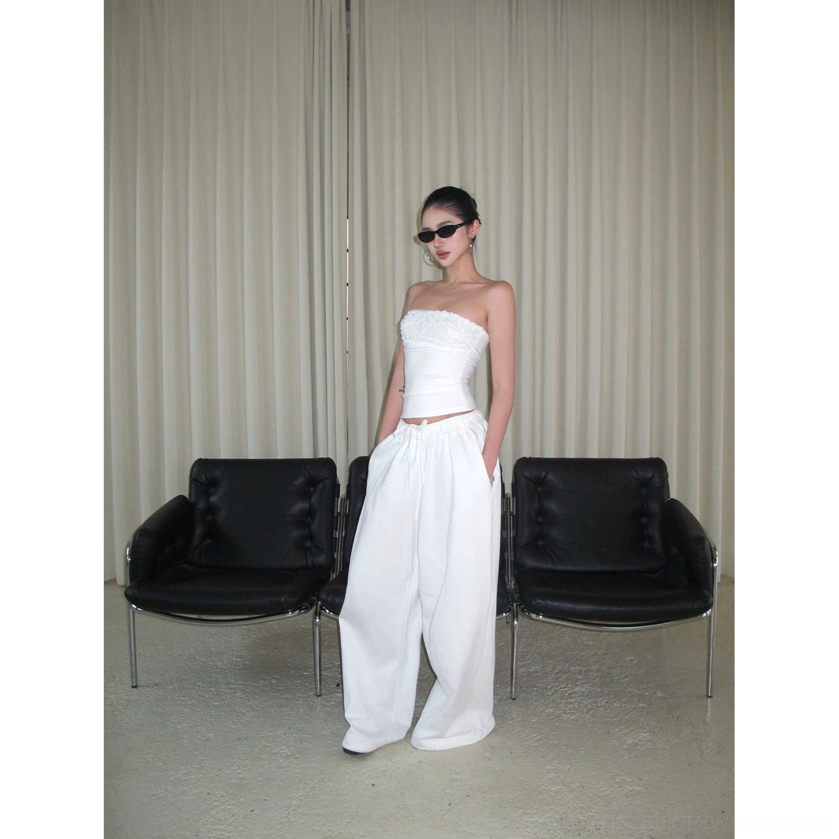 White cotton wide-leg streetwear pants styled with a strapless cropped top in a minimalist lounge, full-body front view