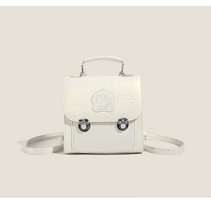 White crested mini satchel crossbody bag in textured crinkle PU with silver buckles, top handle, and adjustable long strap