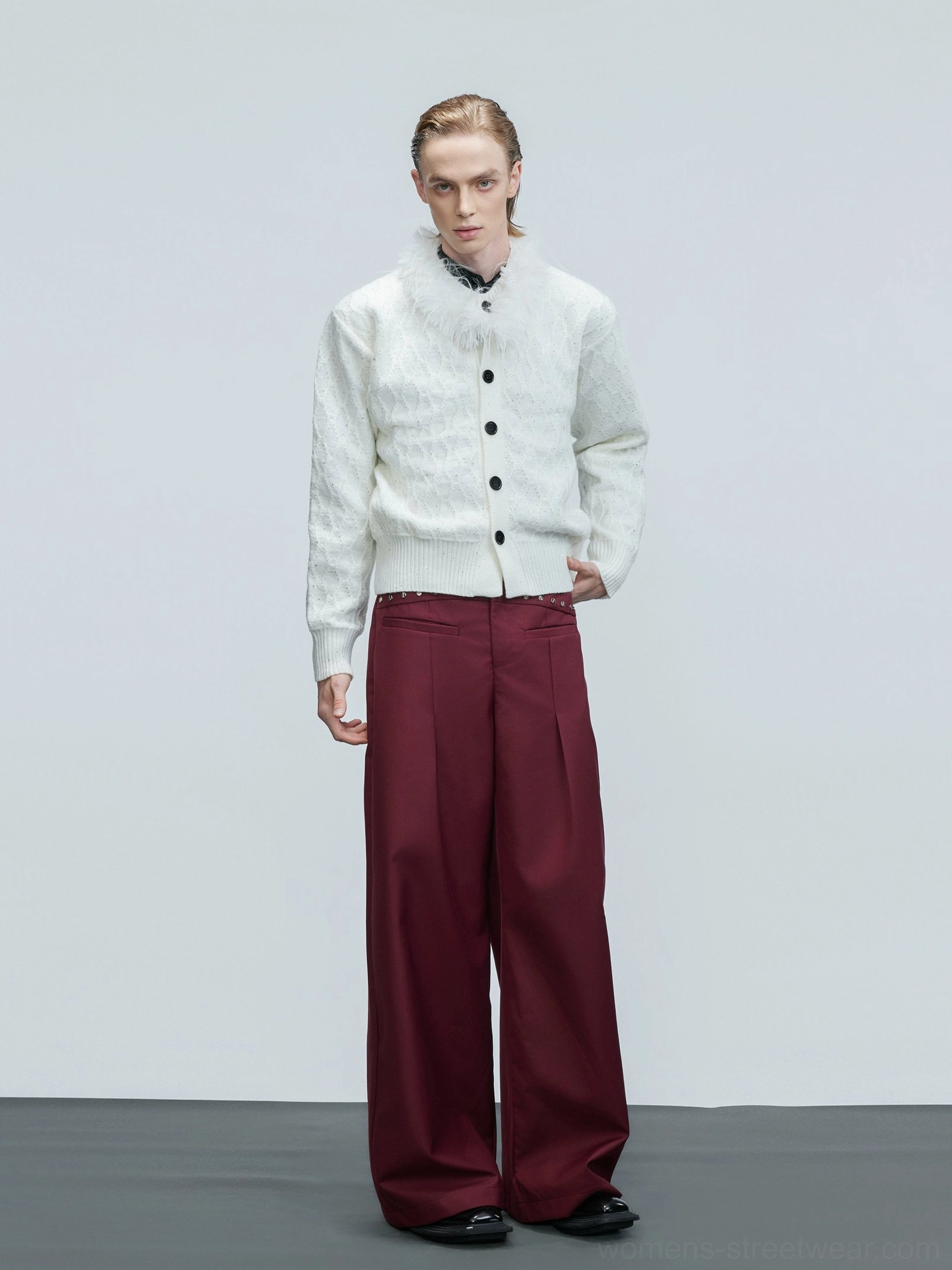White cropped cable knit cardigan with faux feather collar styled with burgundy wide-leg trousers in studio