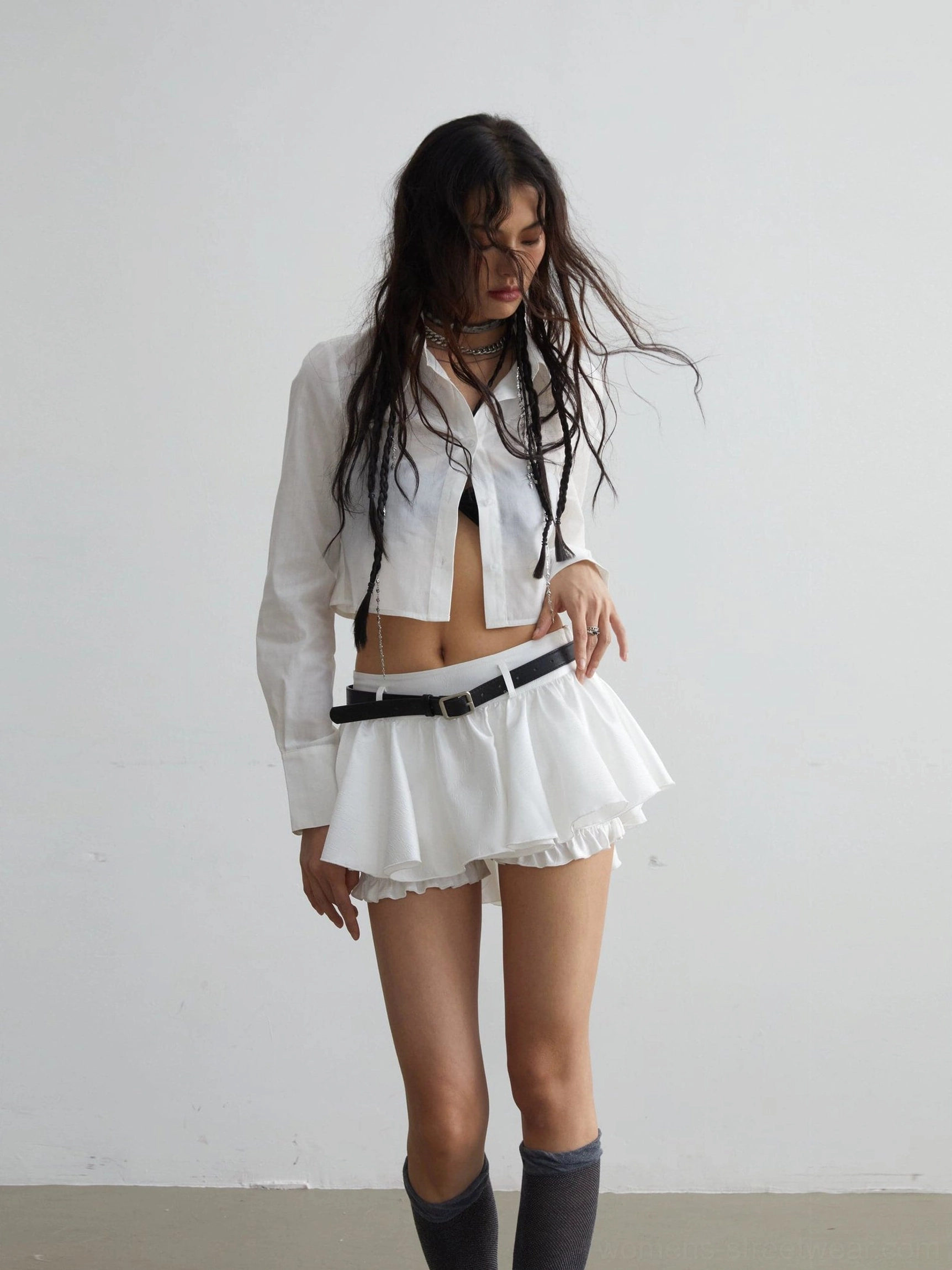 Full front view of a white cropped shirt with long sleeves styled with a ruffled mini skirt and knee-high socks