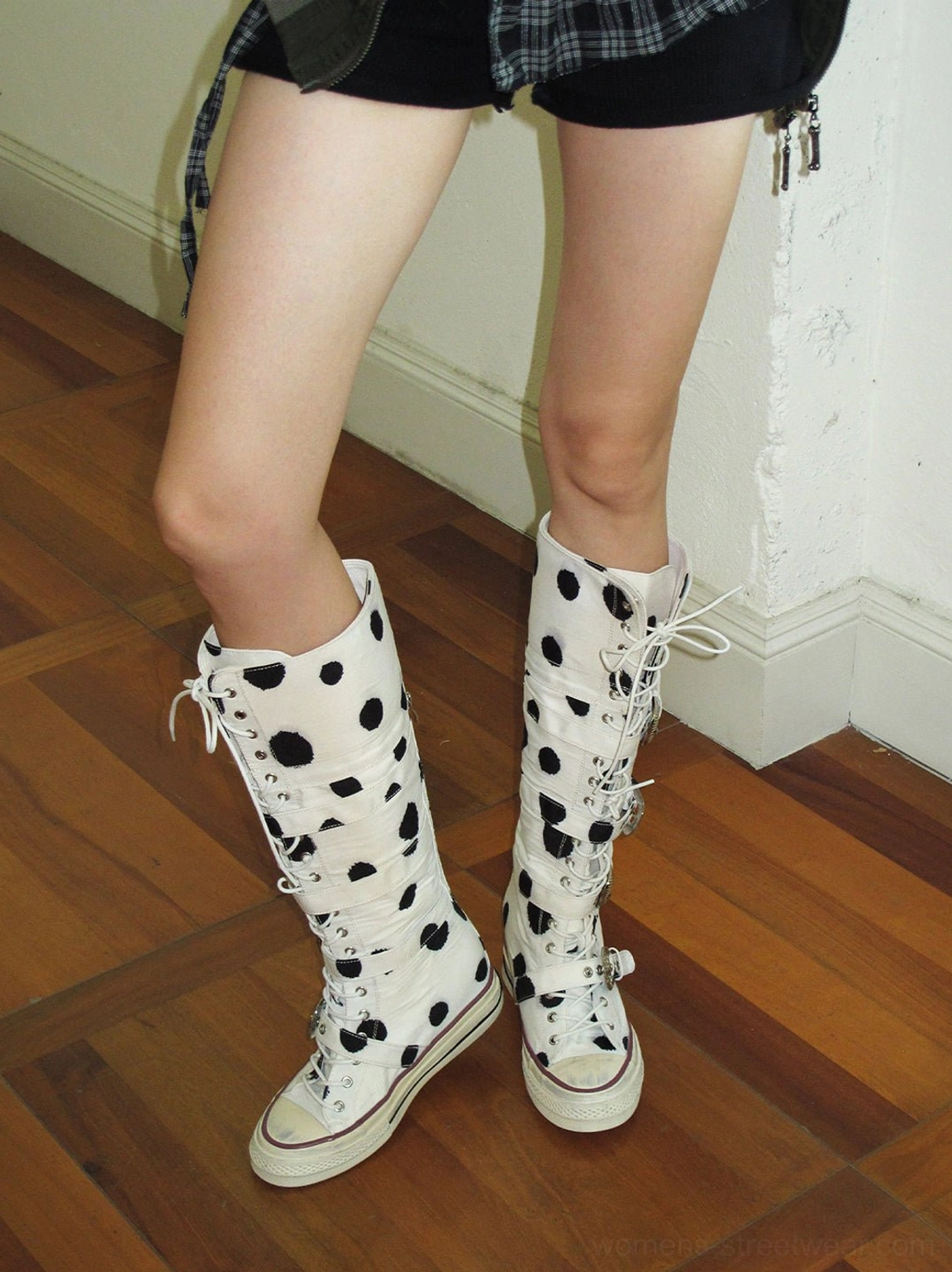 Front view of white Dalmatian print lace-up combat boots with decorative metal buckles styled in Y2K streetwear
