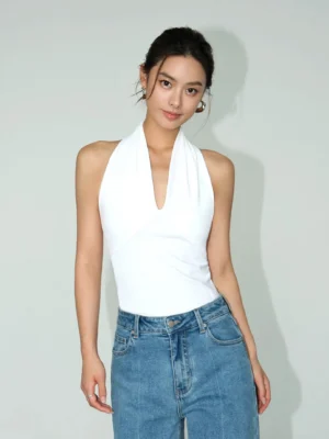 White deep V halter sculpt knit top styled with high waisted blue jeans in a front full view