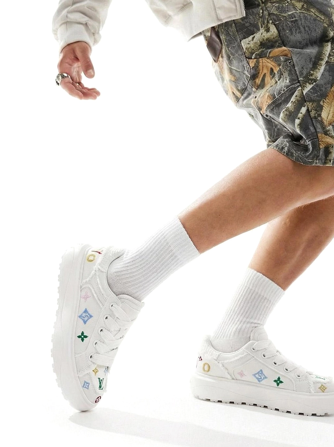 Model walking in white embossed platform skate sneakers with colorful graphic details and chunky streetwear sole