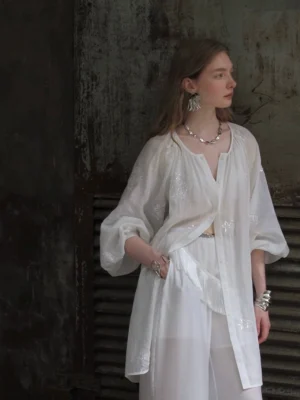 Side view of a white embroidered loose blouse and long flowing skirt outfit with oversized lantern sleeves, subtle floral embroidery, and relaxed East Asian streetwear styling