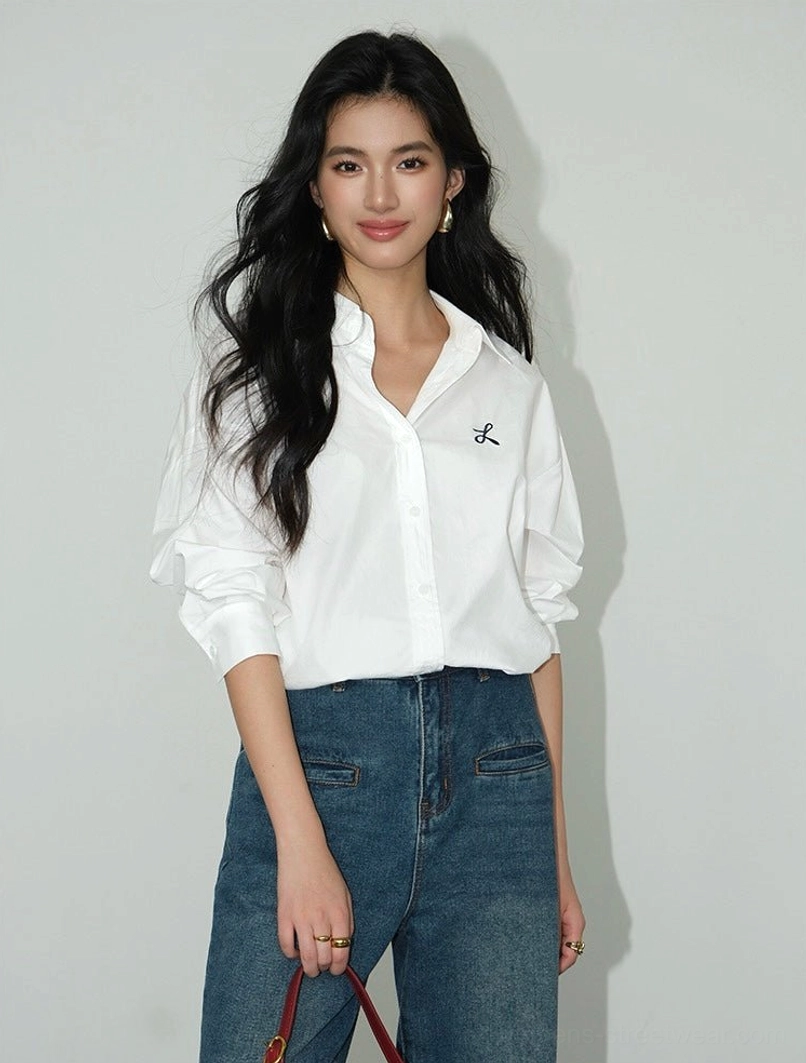White embroidered oversized button-down shirt with classic pointed collar and black chest embroidery styled with blue jeans