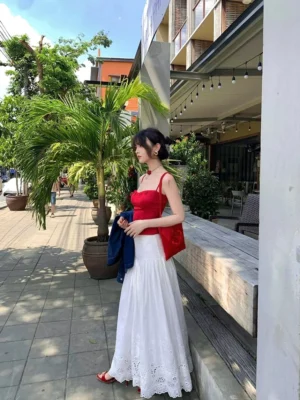 White eyelet lace maxi skirt with flowy A-line silhouette, gathered waist, delicate hollow embroidery hem, and pure cotton fabric styled on a tropical street