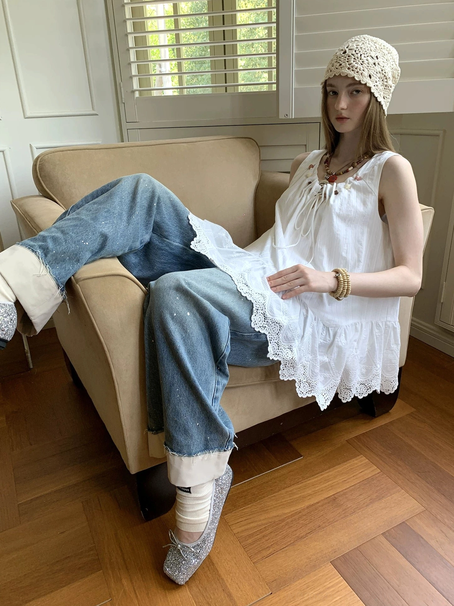 White sleeveless eyelet lace tunic top styled as relaxed boho streetwear with cuffed jeans and layered accessories
