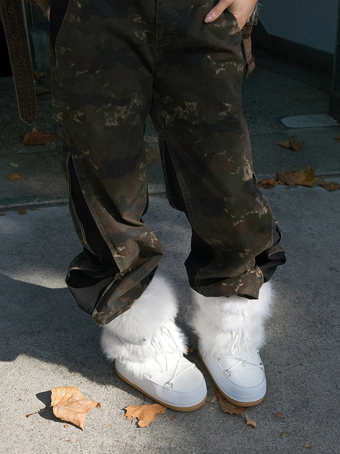 Side view of white faux fur platform snow boots styled with camouflage cargo pants for casual outdoor streetwear