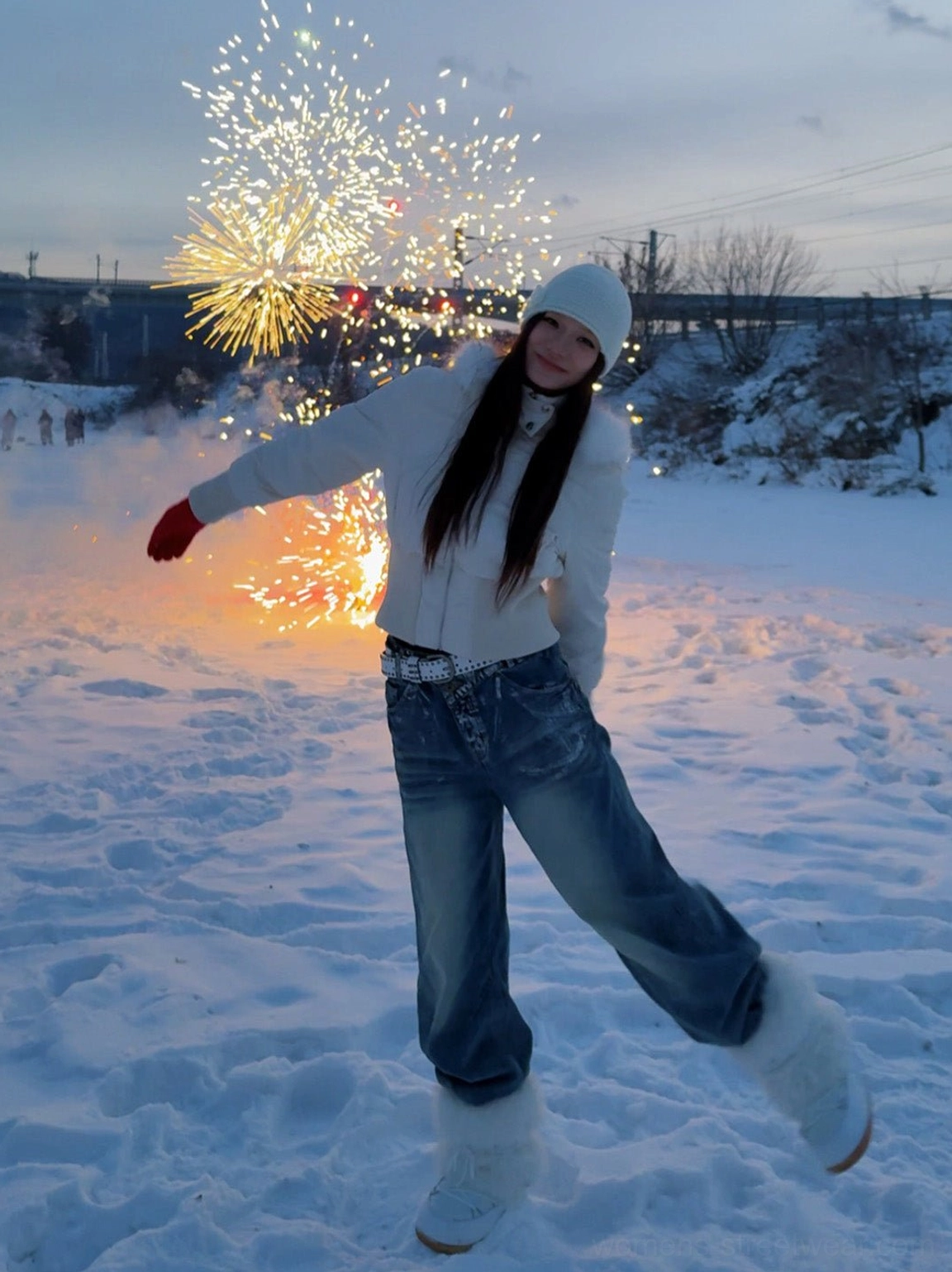 White faux fur platform snow boots worn with a white winter outfit in a snowy outdoor setting with fireworks
