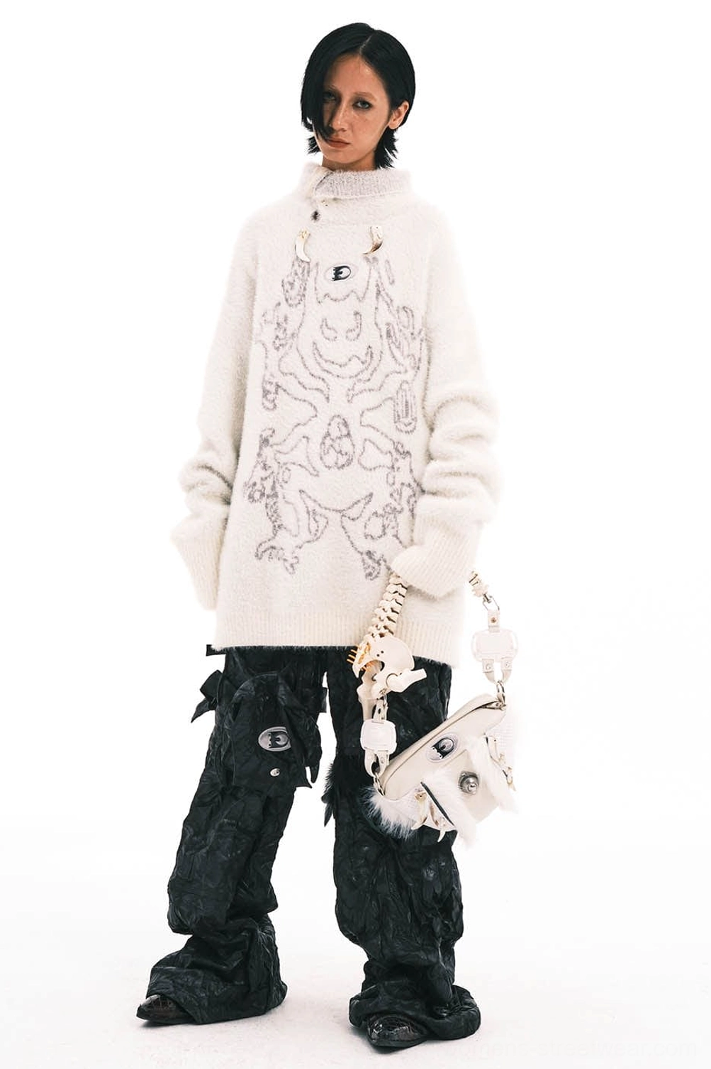 Female model holding cream leather white faux fur skeletal spine handle bag with silver metal hardware