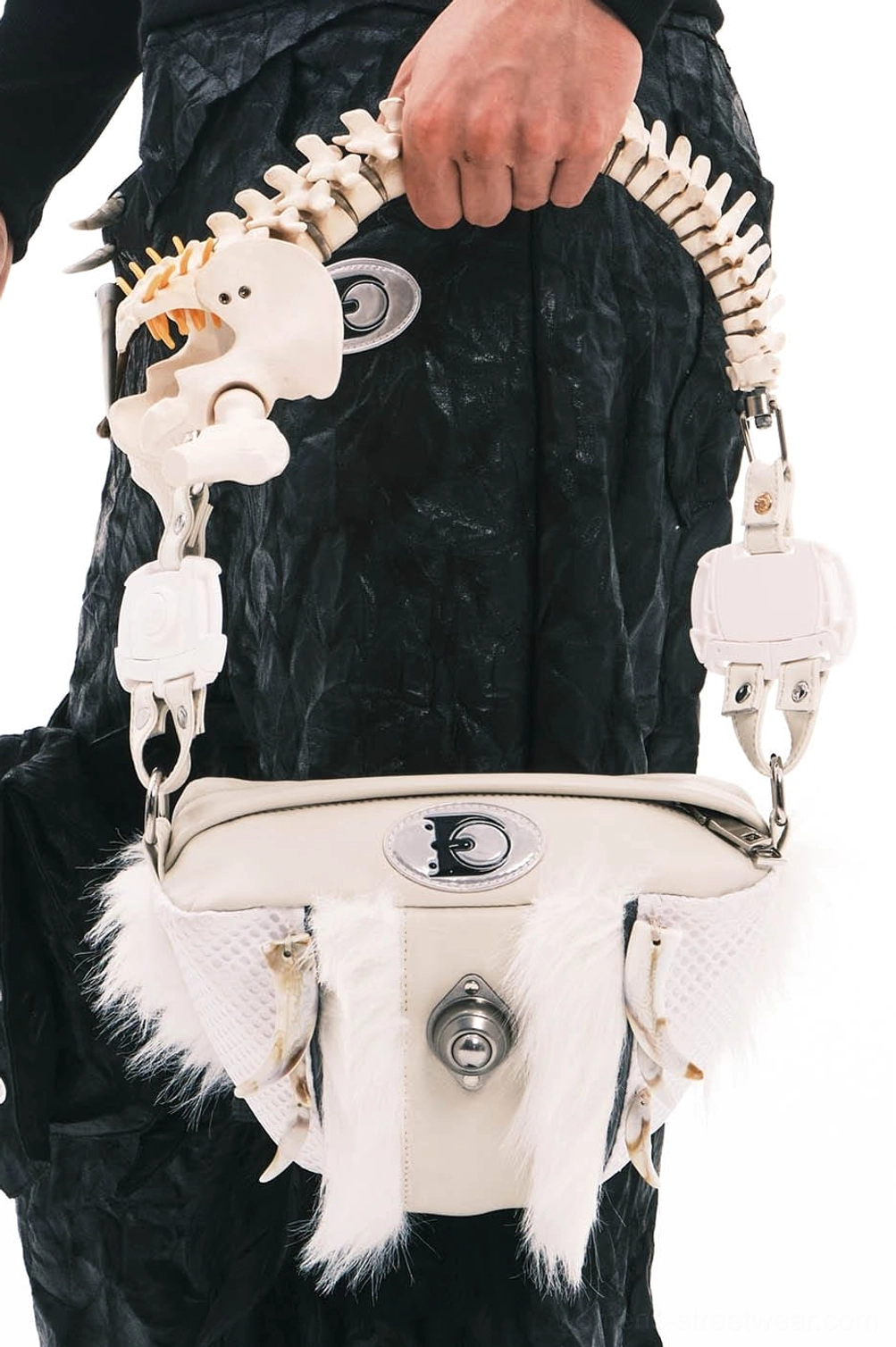 Overhead close-up of white faux fur skeletal spine handle shoulder bag with cream leather, turn-lock closure, and silver hardware