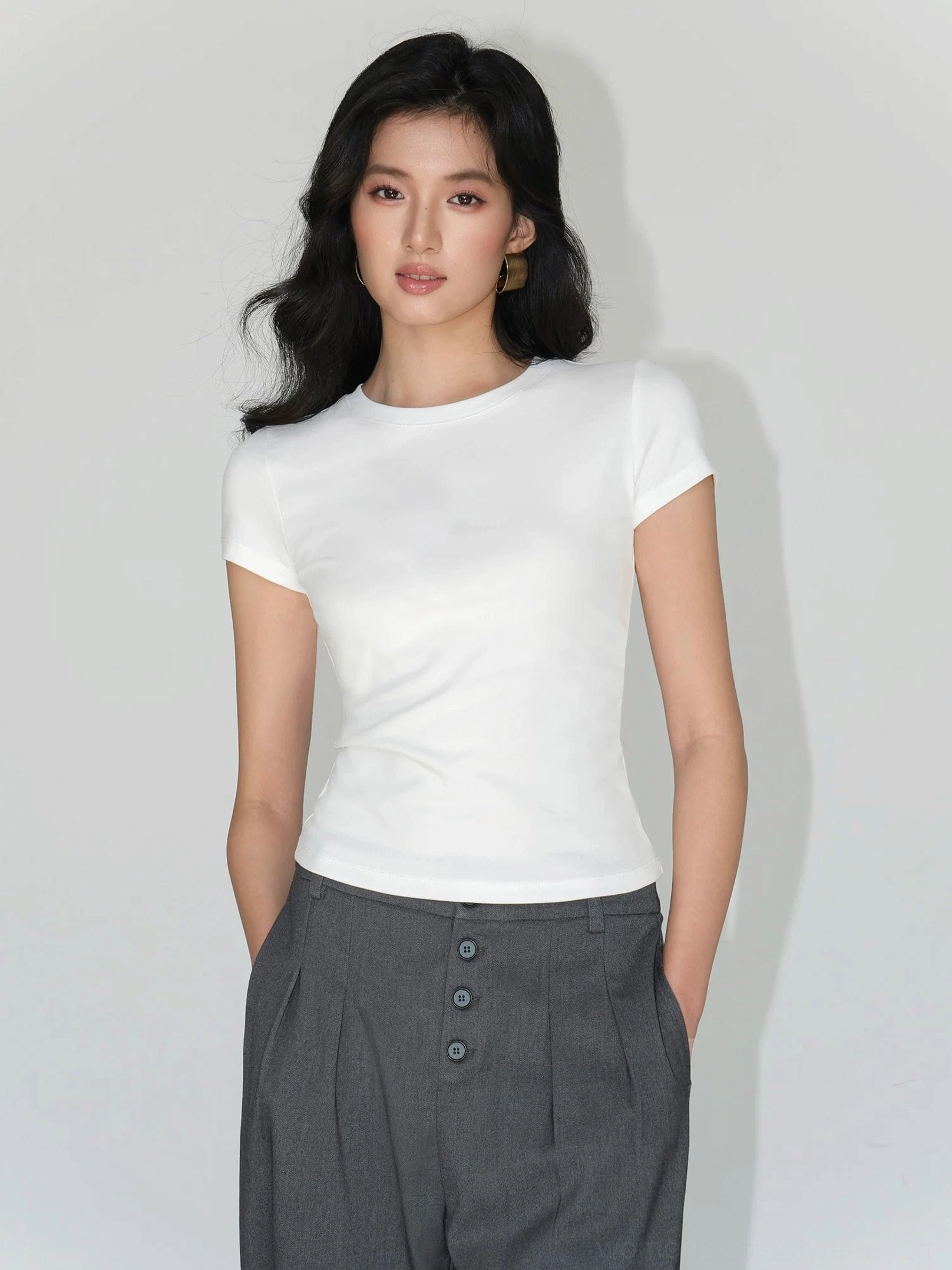 white fitted crew neck short sleeve tee front full body with high waisted gray tailored trousers workwear styling