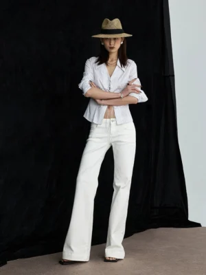 White flare denim jeans styled with a striped shirt and straw hat for a relaxed seaside streetwear outfit