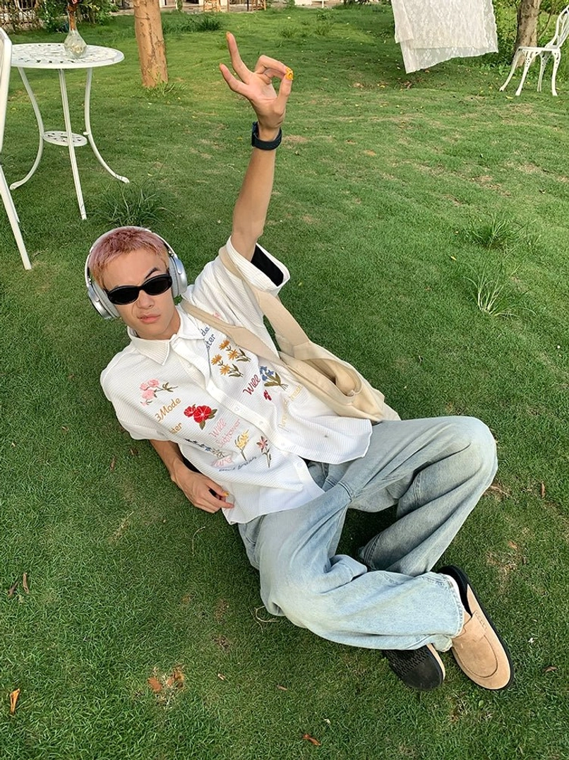 White floral embroidered short sleeve button-up shirt shown in a relaxed outdoor Y2K streetwear outfit with multicolor details