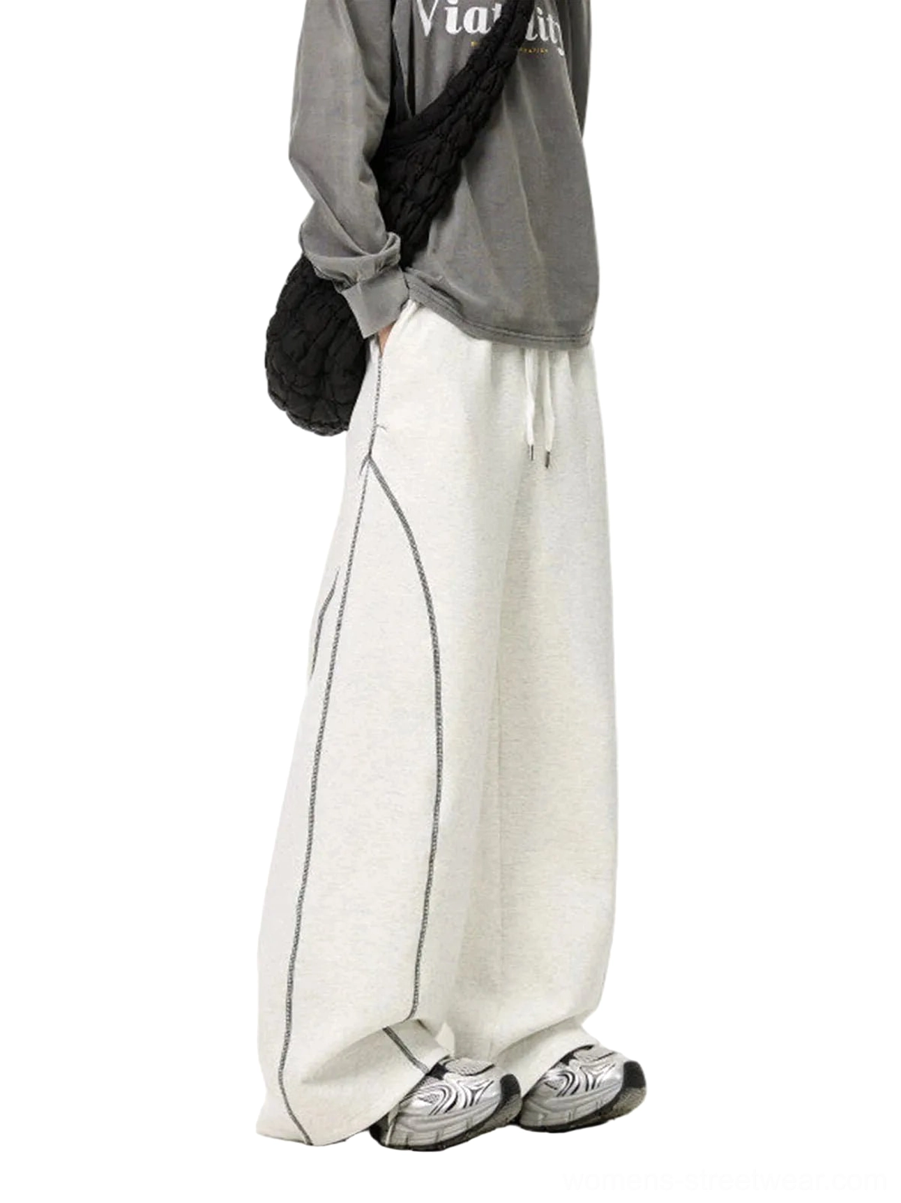 Side profile of White Flower Gray oversized balloon sweatpants showing relaxed wide legs, curved contrast side seams, elastic drawstring waist, and retro streetwear outfit
