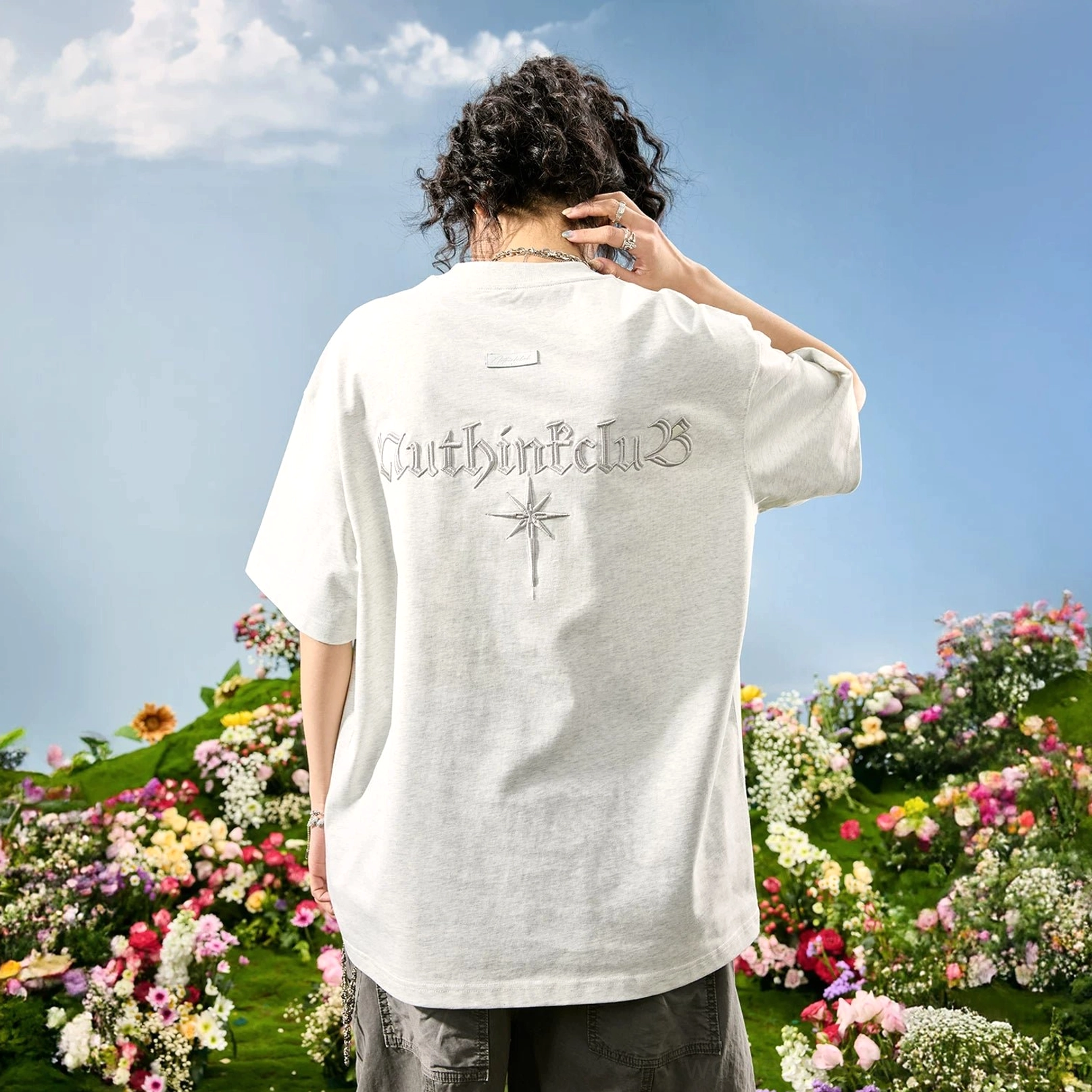 White flower gray oversized Gothic embroidered back T-shirt on female model, featuring tonal lettering and compass-inspired starburst motif