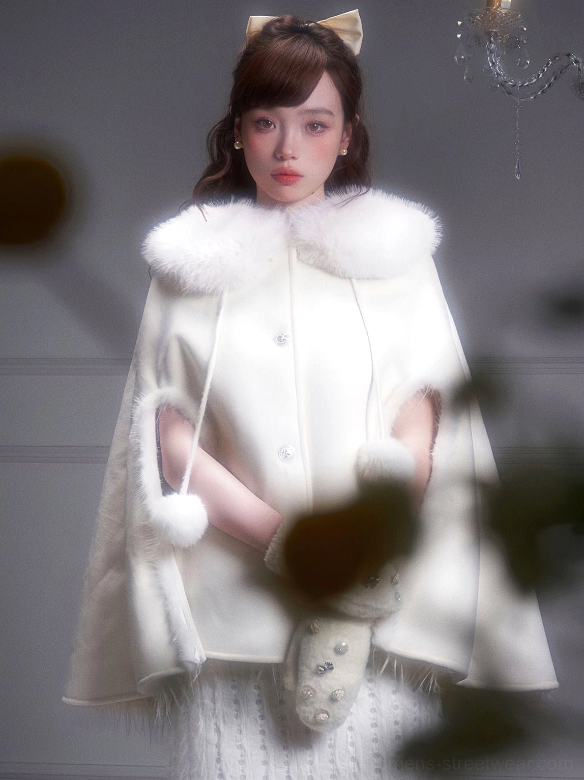 White fur trimmed cape coat side detail showing arm opening pom-pom drawstring and elegant winter silhouette