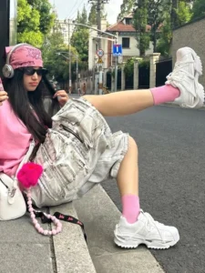 White futuristic chunky runner sneakers styled with a pink top, grey cargo shorts, bandana, and sunglasses in a Seoul-inspired casual streetwear outfit