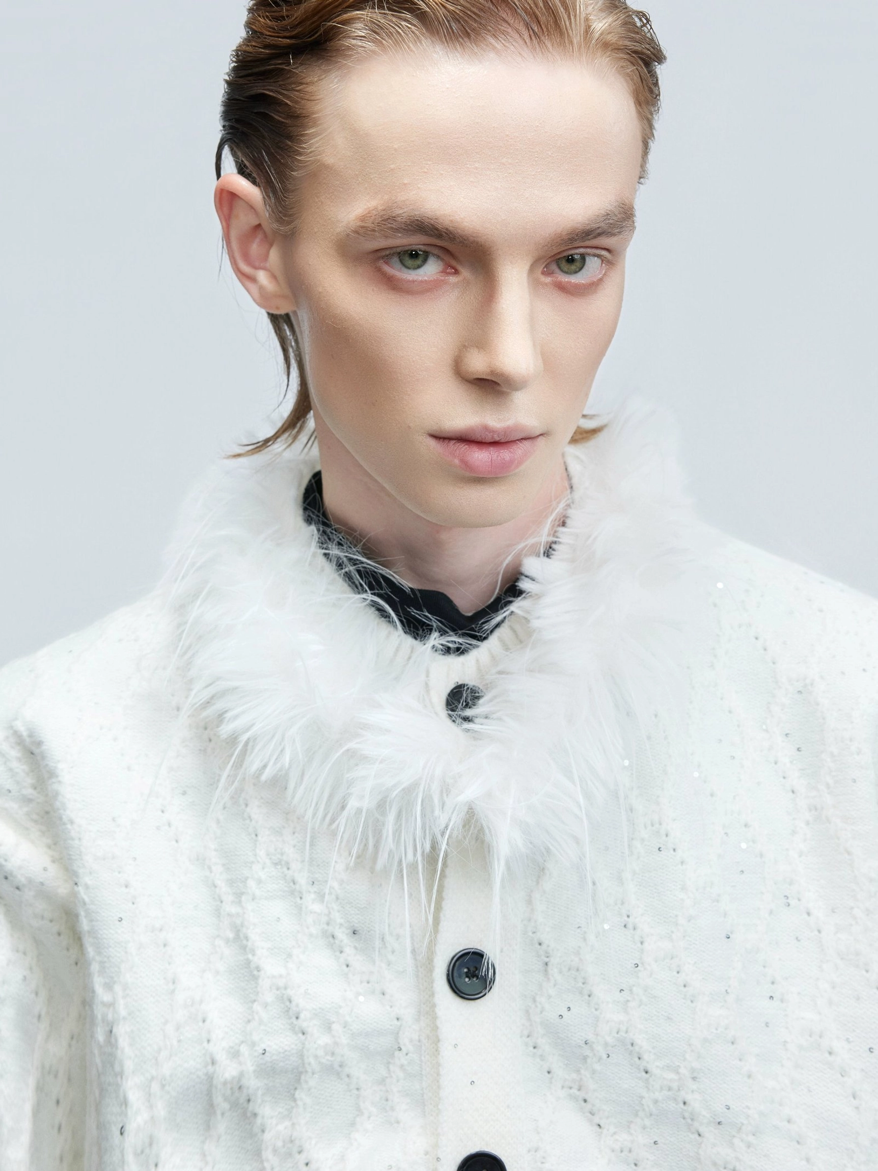 Close-up of white glitter cable knit cardigan with fluffy detachable faux feather collar and contrasting black buttons