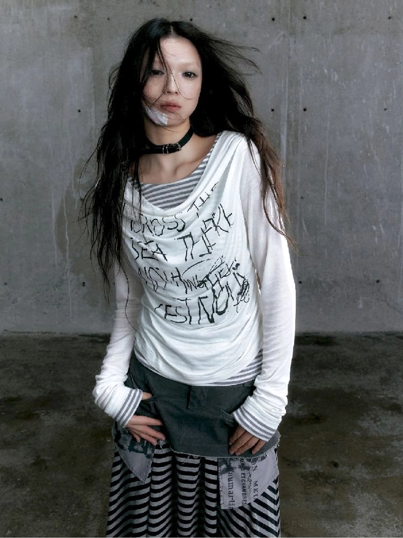 Close view of white graffiti layered long sleeve top with draped asymmetric neckline and striped base layer