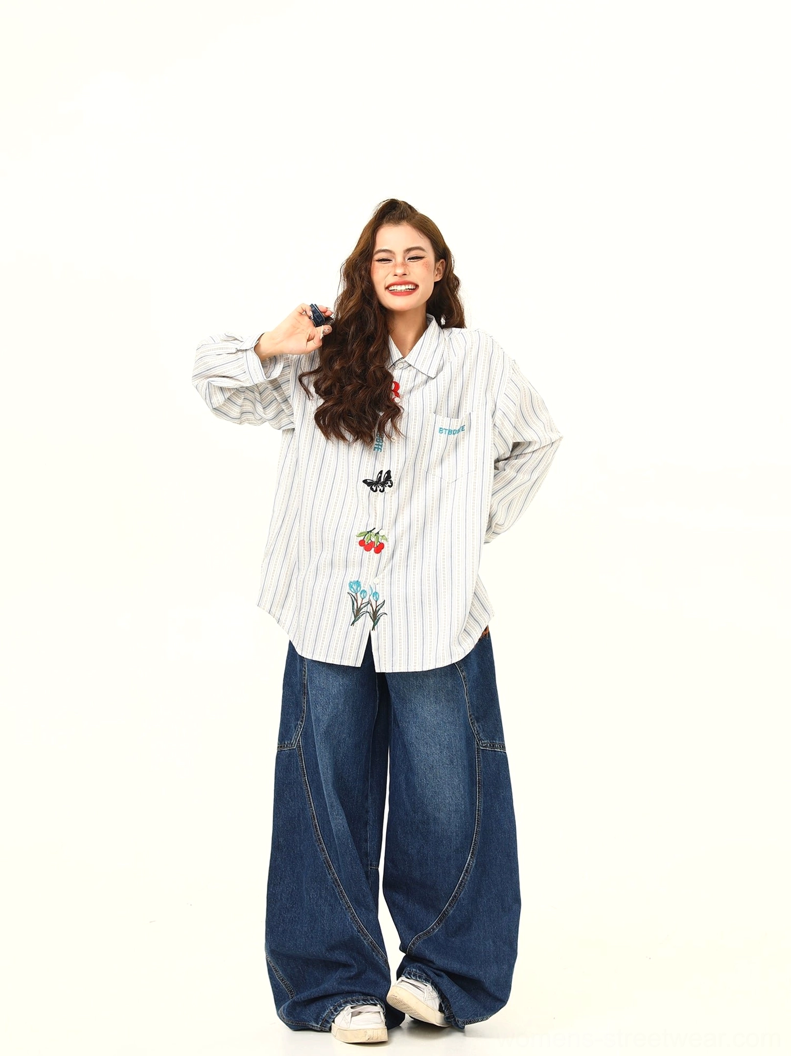 Smiling model wearing a white and gray oversized embroidered striped shirt with cute floral and cherry details in Korean streetwear style