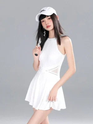 Three-quarter front view of a white halter tennis dress romper with crisscross mesh waist cutout, flared mini skirt, white baseball cap, and tennis racket