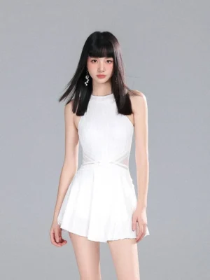 Front view of a white sleeveless halter tennis dress romper with fitted bodice, high neckline, pleated flared mini skirt, and clean monochrome styling