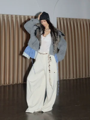 White high waisted wide leg cargo trousers on a female model with contrast panel stitching, utility pockets, decorative chain belt, beanie, and layered necklaces