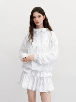 White hooded windbreaker and ruffle mini skirt set with chest logo and contrast drawstring shown on a model