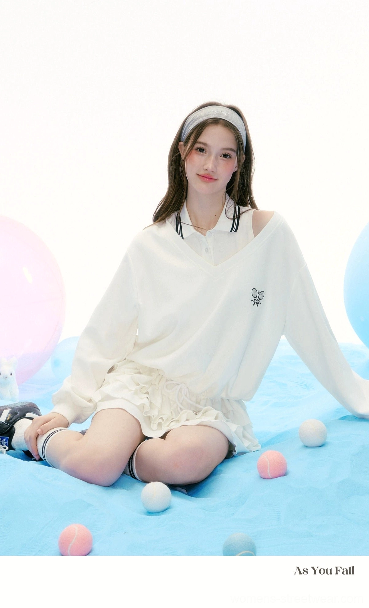 White Korean preppy tennis two piece outfit with cutout shoulder polo top and layered ruffle skirt in a seated pose