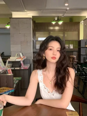 White lace neckline camisole dress styled with gold necklace and drop earrings in a vintage cafe setting