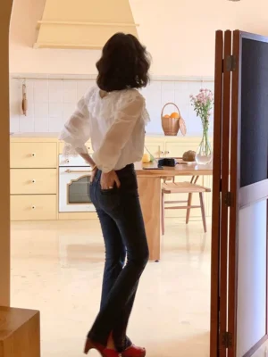 Back view of white lace ruffle blouse showing the delicate rear lace detailing and relaxed silhouette styled with dark flare jeans and red heels