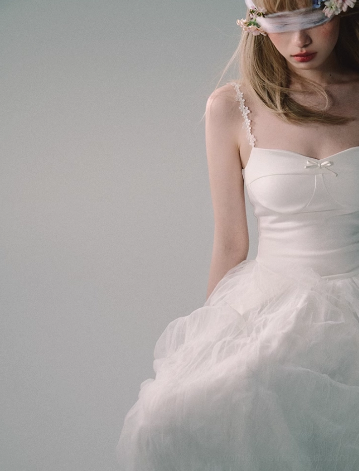 Three-quarter side view of white lace strap tulle gown featuring a sweetheart bust, mini bow, fitted bodice, and soft layered skirt