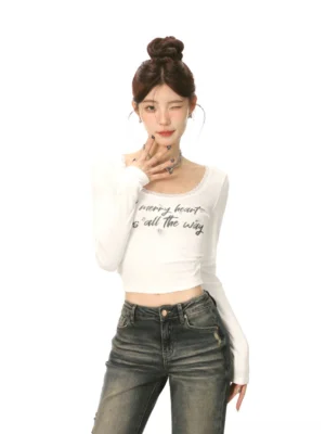 Front close-up of a white lace trim U-neck cropped long-sleeve streetwear top with handwritten lettering and a fitted waist-exposing silhouette