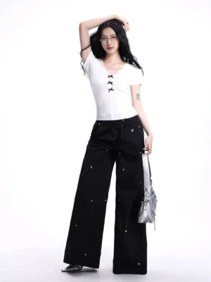 White lace-up bow V-neck ribbed crop baby tee styled with high-waisted wide-leg pants and a silver shoulder bag in a studio front view