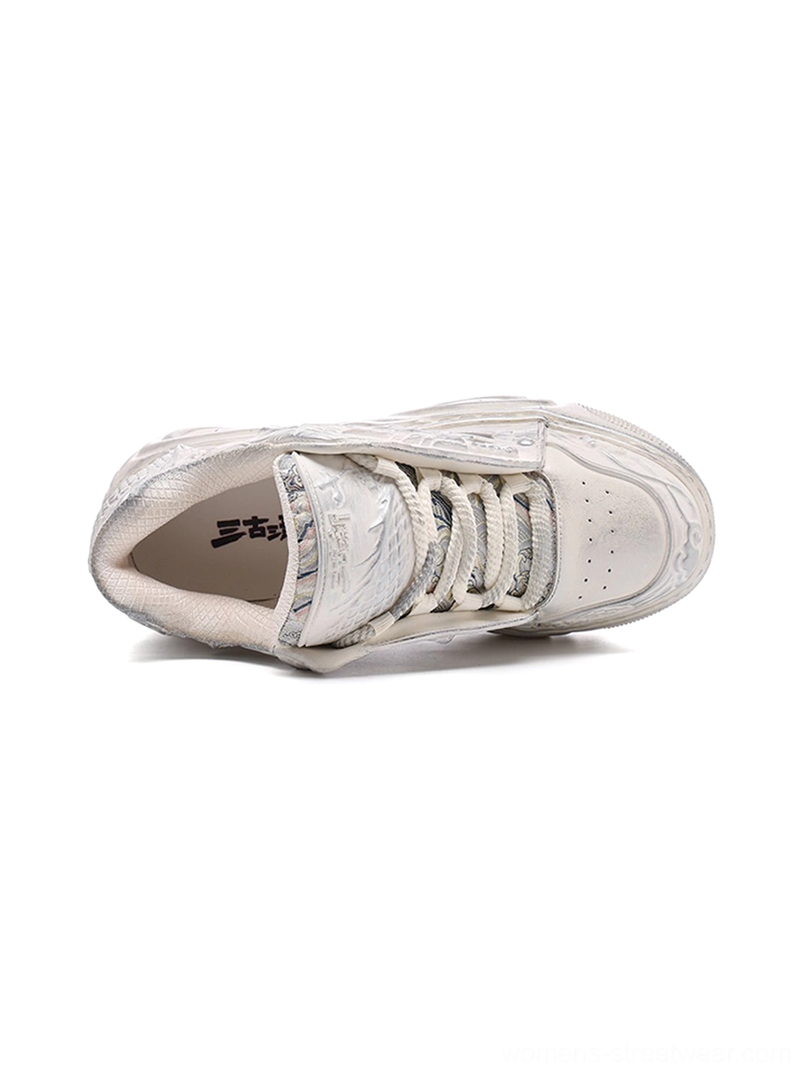 Top-down view of white lace-up dragon relief platform sneakers showing the embossed side panels and insoles