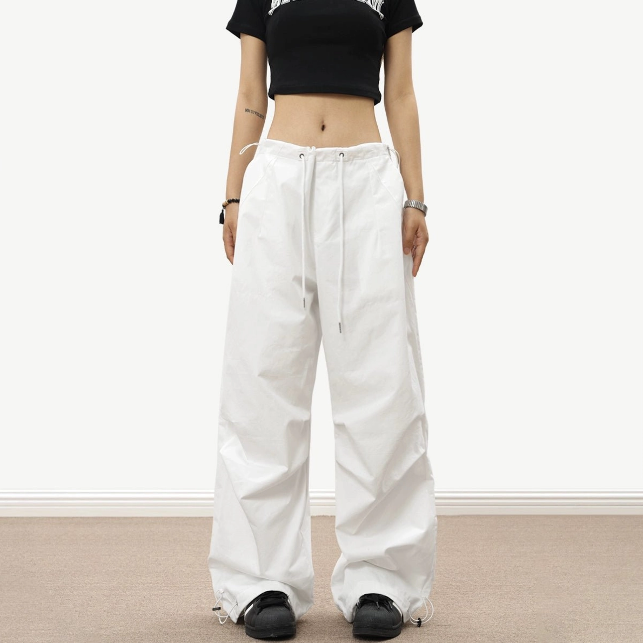 White lightweight nylon parachute wide-leg streetwear pants with smooth fabric, adjustable waist, and relaxed oversized fit