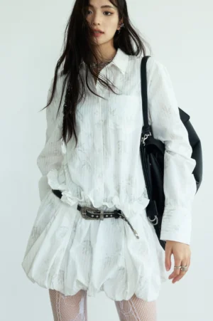 White linen bubble hem shirtdress front view with long sleeves classic collar tonal print studded belt and black shoulder bag