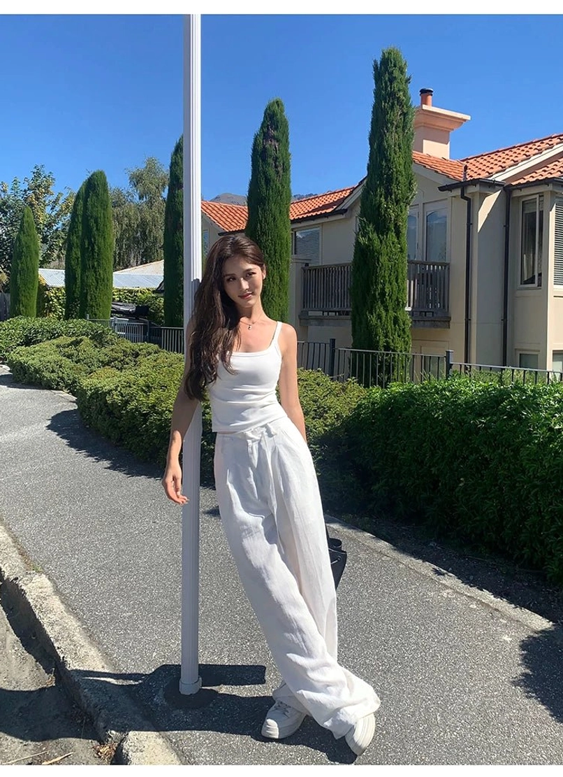 White linen high-waisted wide leg pants with striped long-sleeve top, street shot at vintage stone building roadside location