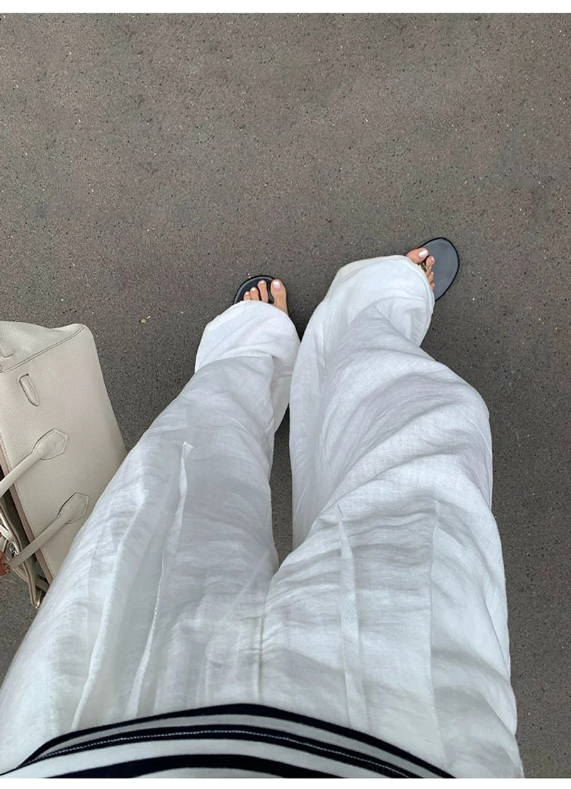 White linen wide leg pants worn overhead view with striped waistband detail, home floor background with leather tote bag styling