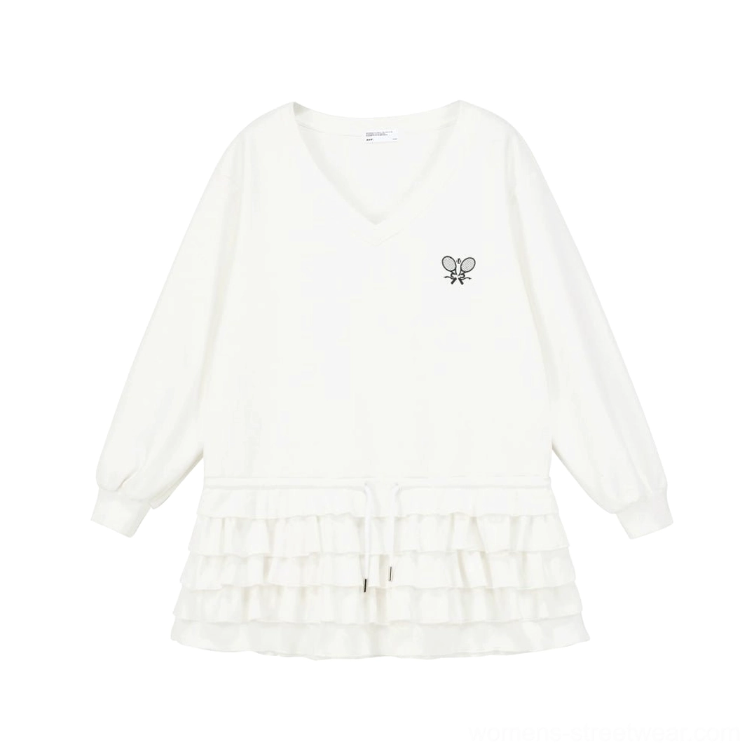 Flat lay of white long sleeve tennis polo top with dual racket embroidery, V neckline and layered ruffle hem