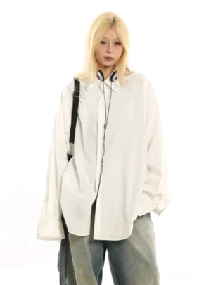White loose oversized button down shirt with pointed collar styled in a Korean streetwear outfit with headphones