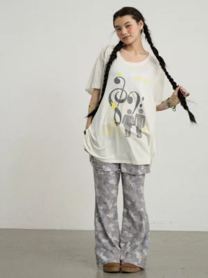 Asian woman wearing a white oversized music note graphic tee with grey camouflage flared pants in a Korean streetwear outfit