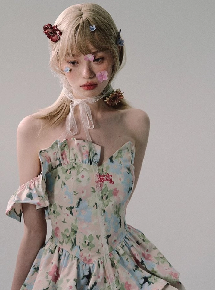 Detailed front view of a white off-shoulder floral ruffle mini dress showing front zipper closure, soft floral texture, and decorative chest embroidery