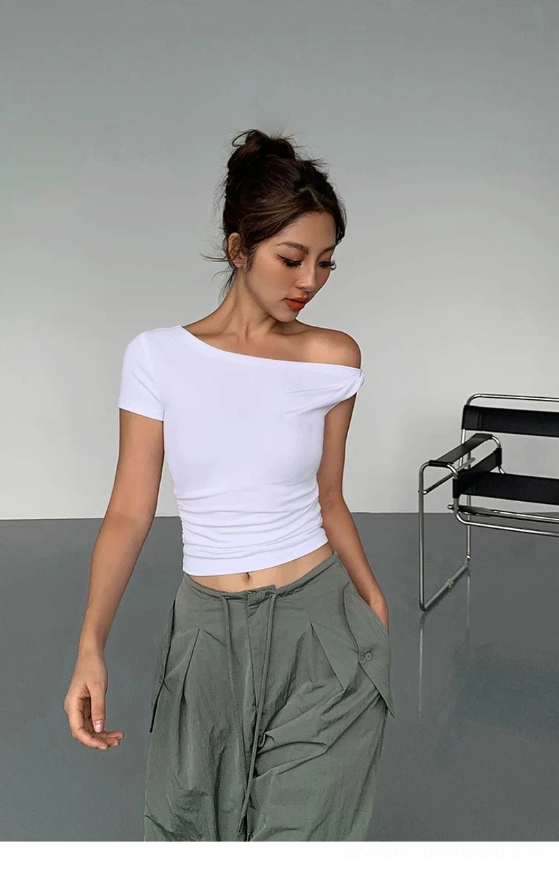 White one-shoulder cropped knit top with a fitted waist styled with army green cargo pants in a minimalist studio