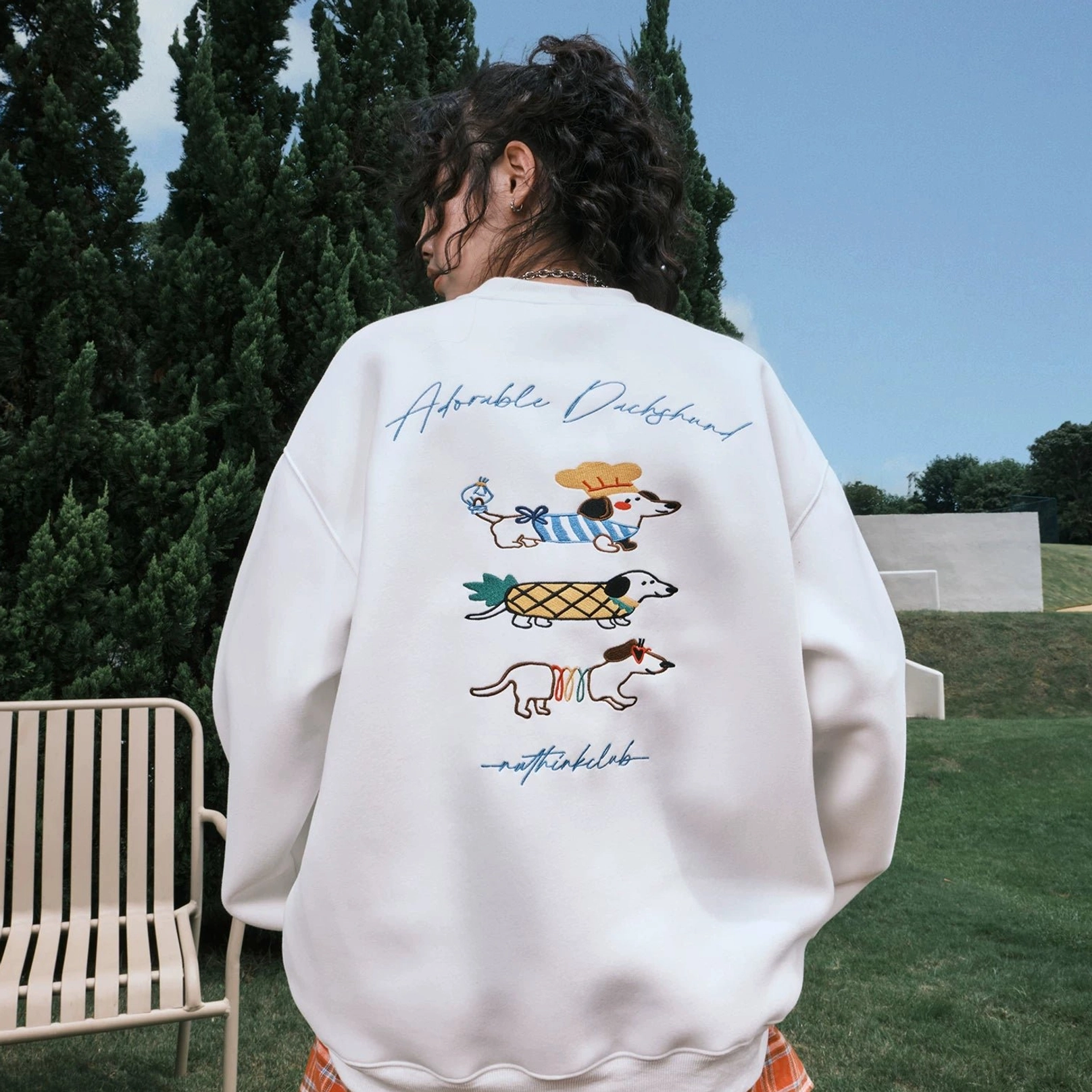 White oversized dachshund graphic sweatshirt with three colorful dog illustrations and handwritten lettering across the full back