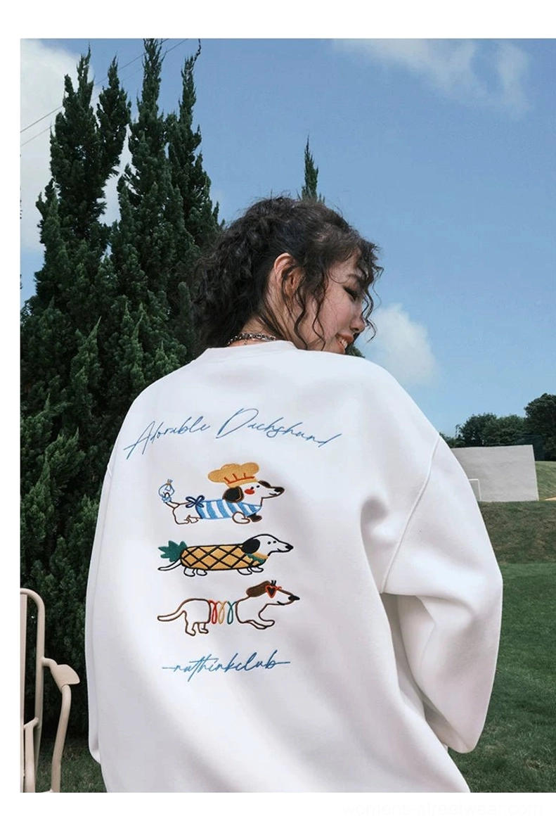 White oversized dachshund graphic sweatshirt shown from the side rear view with colorful embroidered-style dogs and a loose streetwear fit