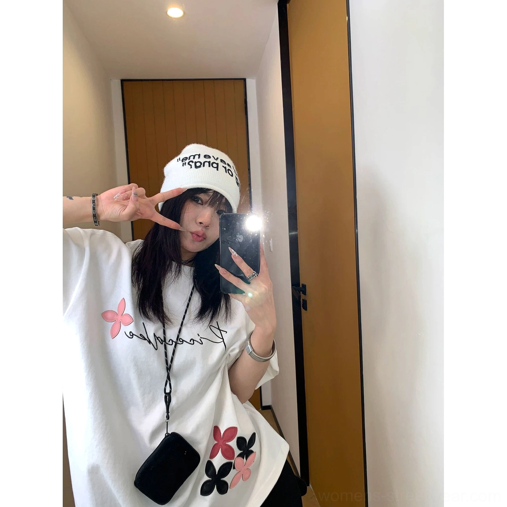 Close-up mirror selfie of a white oversized floral script T-shirt showing the cursive chest print, two-tone flowers, and casual Korean streetwear styling