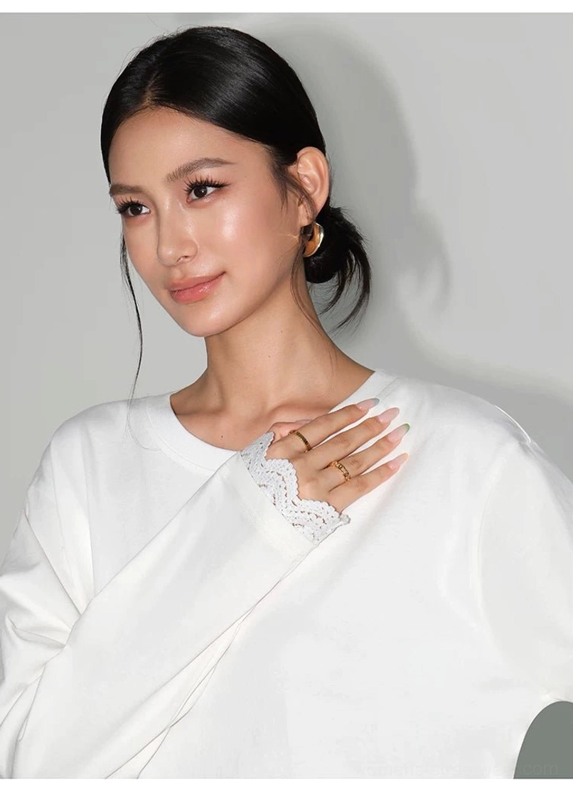Close-up of the white oversized long-sleeve tee dress showing the clean crew neckline and delicate lace-trimmed sleeve cuff
